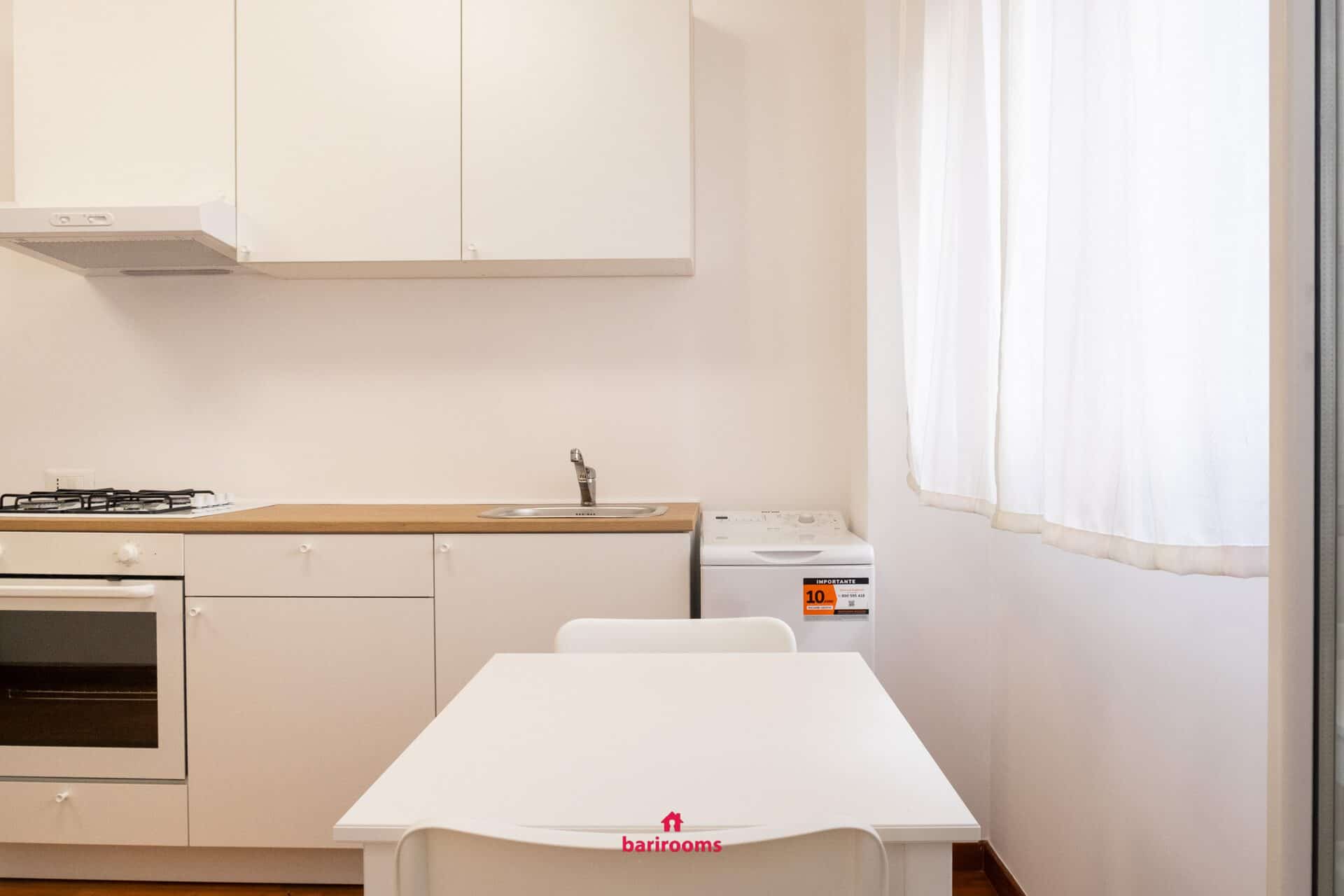 Zona pranzo con tavolo e cucina, appartamento Maison 30 Bari